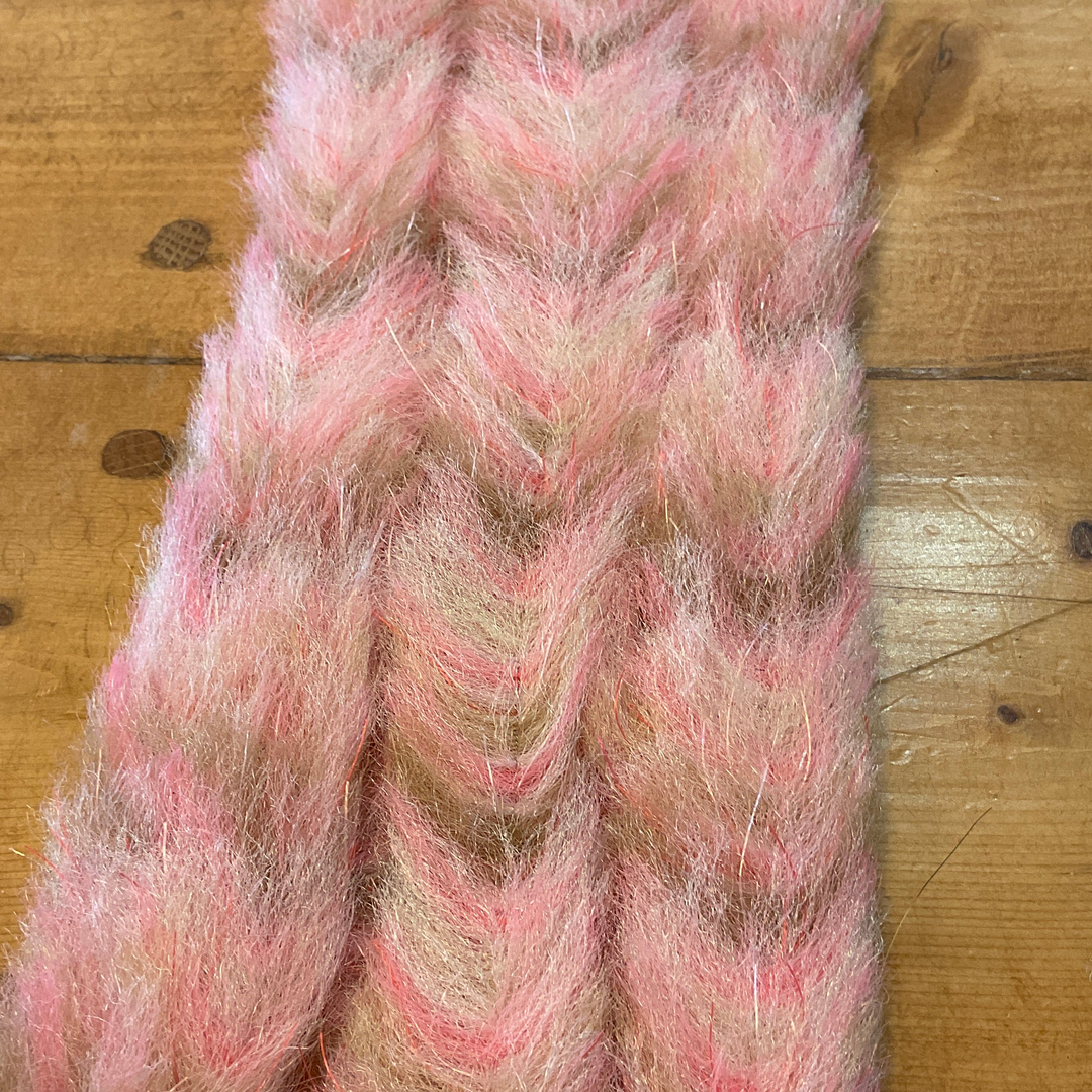 Pink and beige variegated brush with red and silver reflective threads on wooden surface
