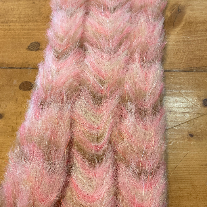 Pink and beige variegated brush with red and silver reflective threads on wooden surface