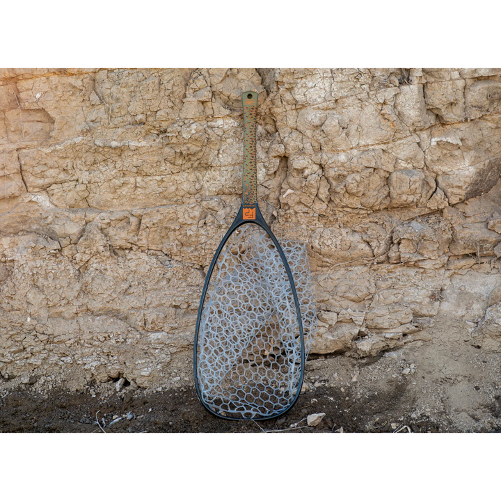 Fishpond Nomad Emerger Net leaning against rock wall showing full length and slim profile