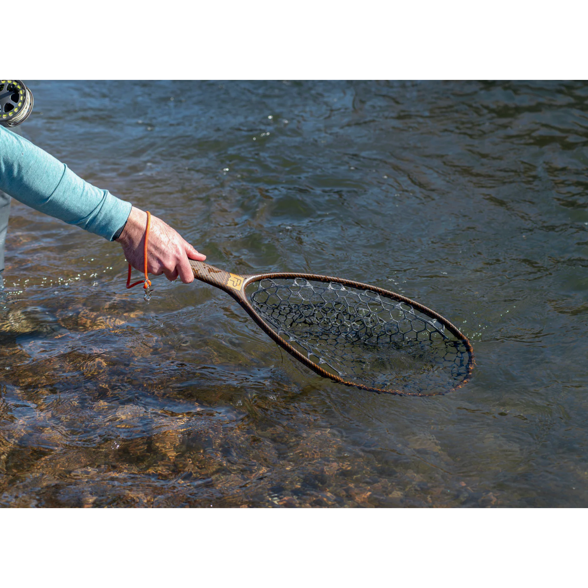 Fishpond Nomad Native Net River Armor 2.0 carbon fiber handle with orange lanyard in river