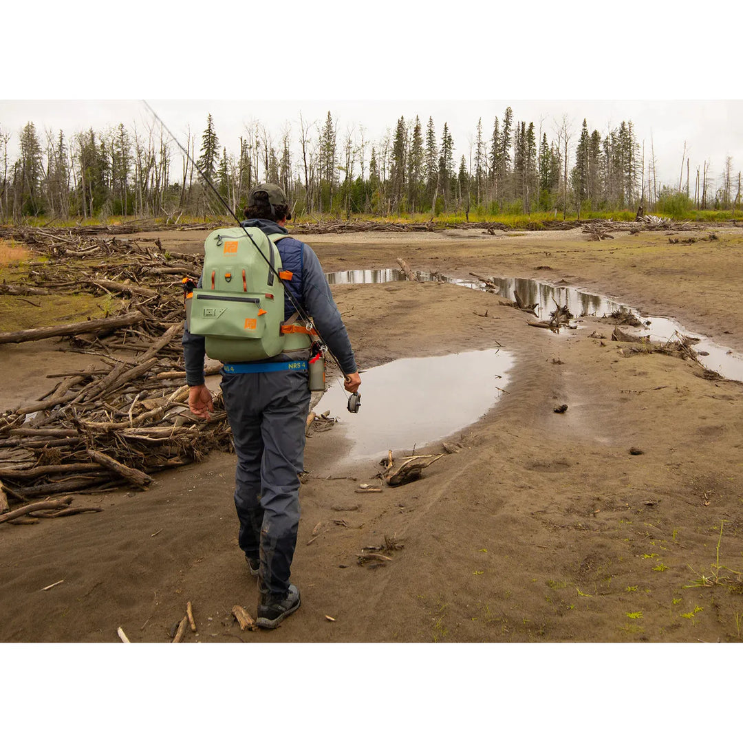 Fishpond Thunderhead Submersible Pouch attached to backpack in marshy fishing landscape