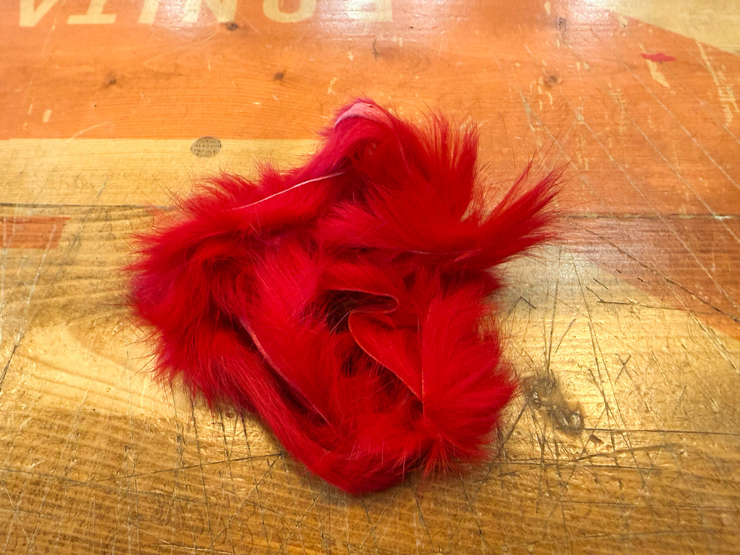 Bright red rabbit fur strips showing fuzzy hair and leather backing
