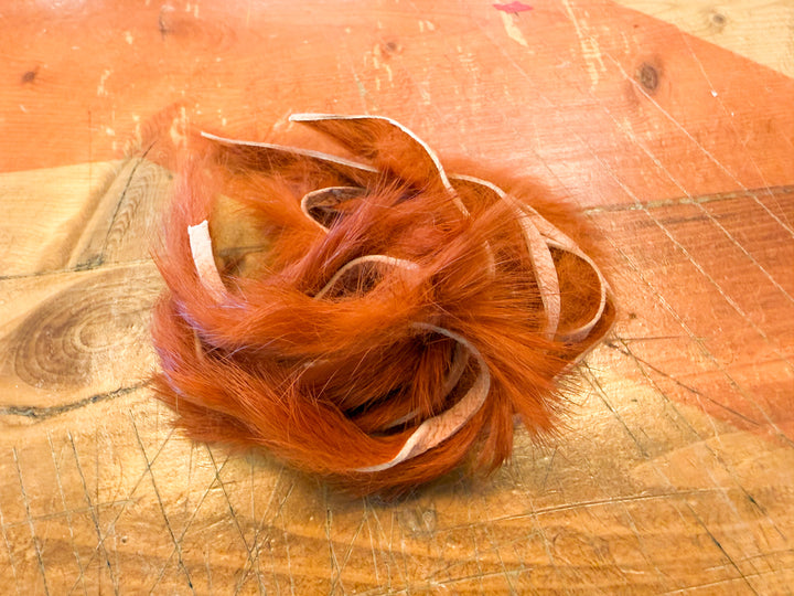Reddish orange flame rabbit fur strips tangled pile