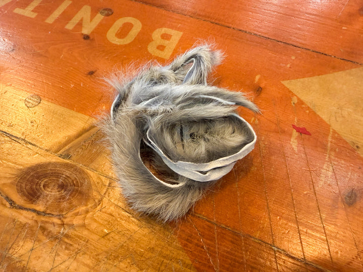 Grey silver rabbit fur strips with darker tips on wood