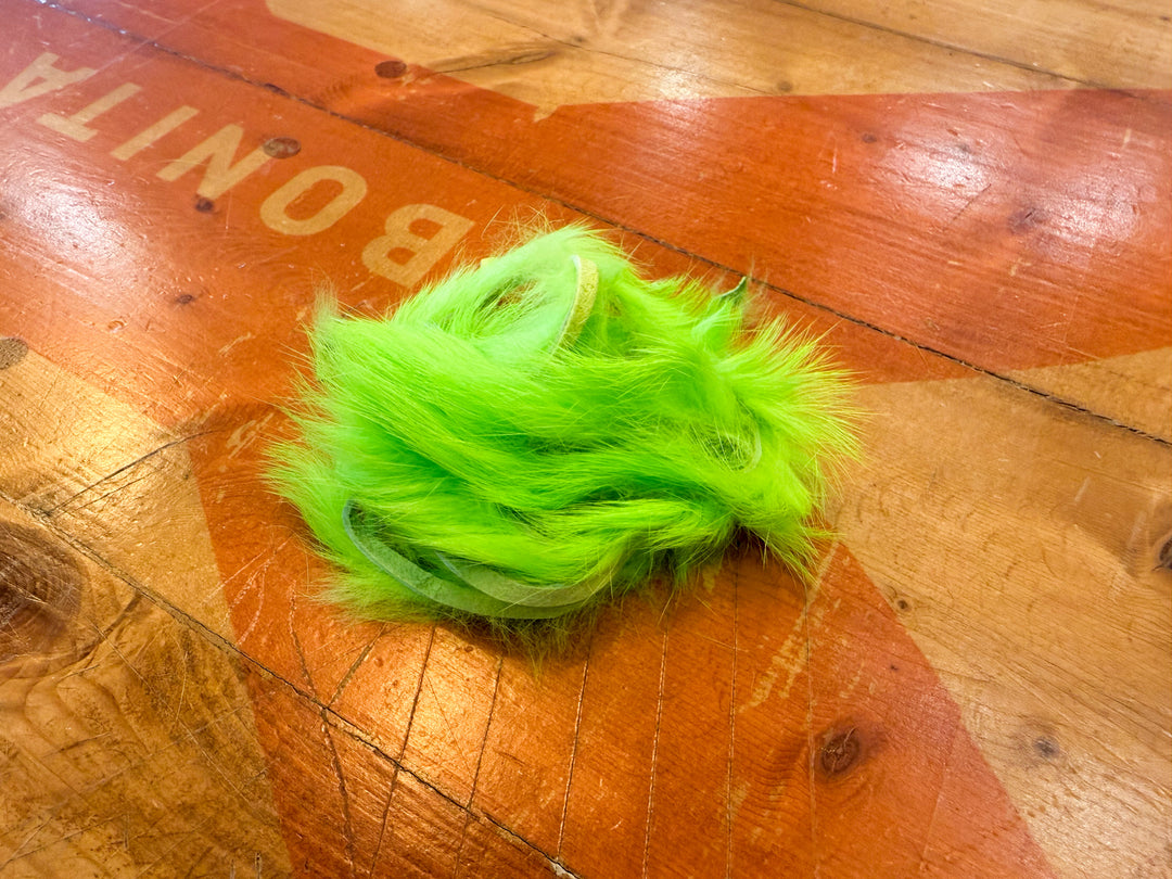 Neon green rabbit fur strips for fly tying on wooden surface