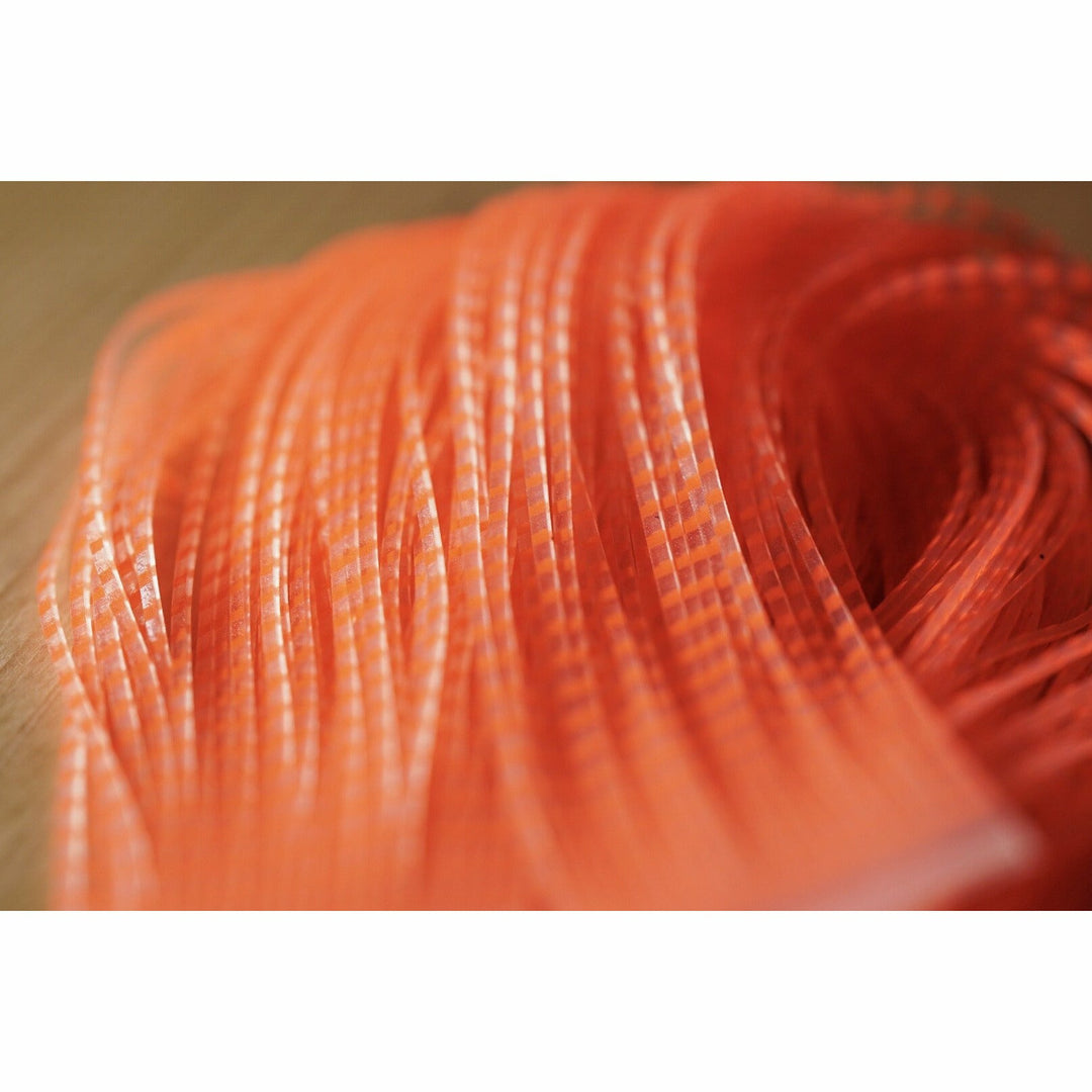 Close-up of fluorescent orange barred clear silicone fly tying leg texture