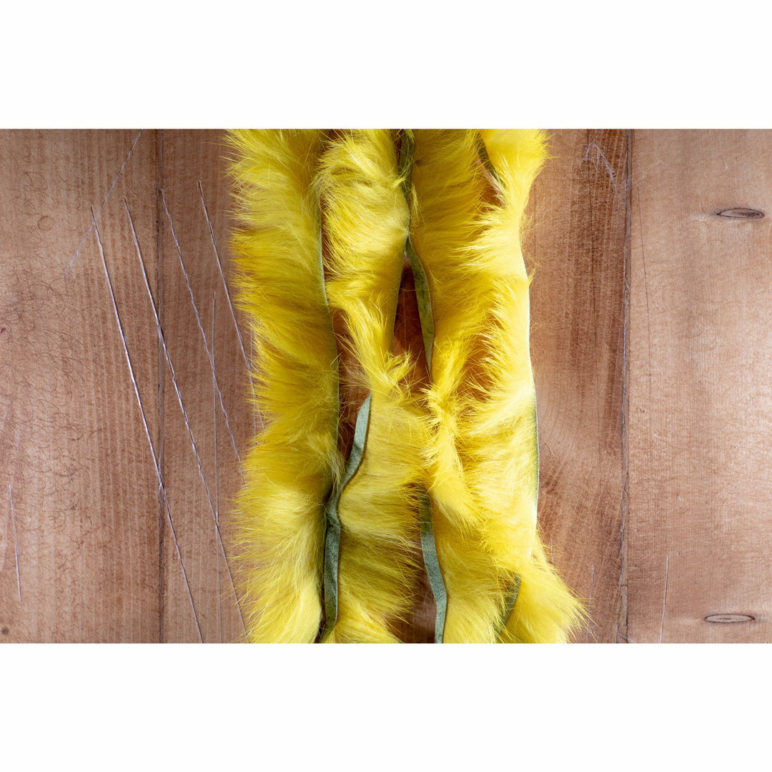 Bright yellow crosscut rabbit fur strip on wooden surface