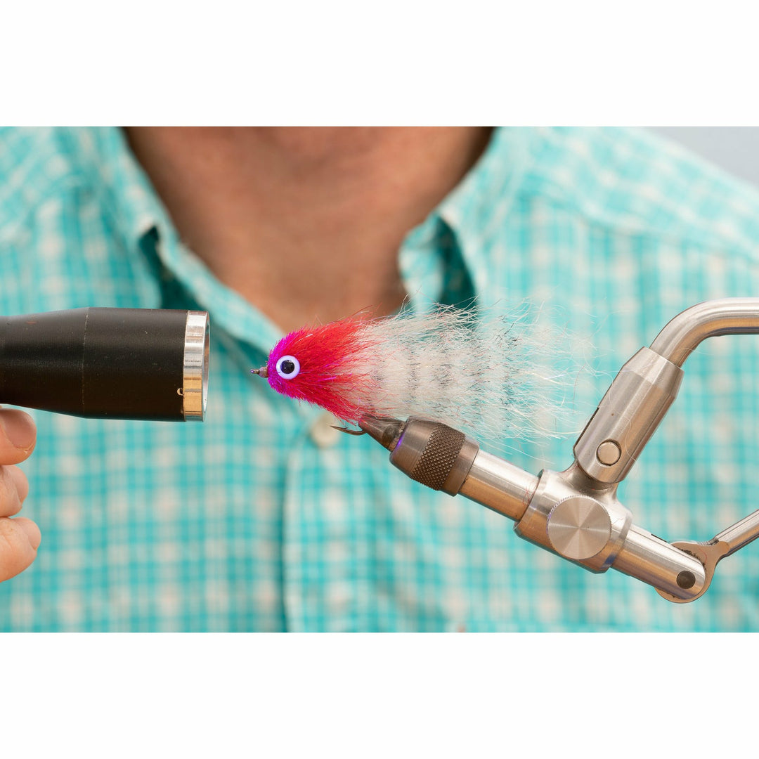 Side profile of DL3 Minnow fly with pink head and glowing translucent tail under light