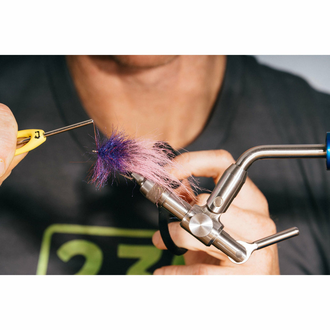 Adjusting fuzzy purple and pink fibers on fly tying vise