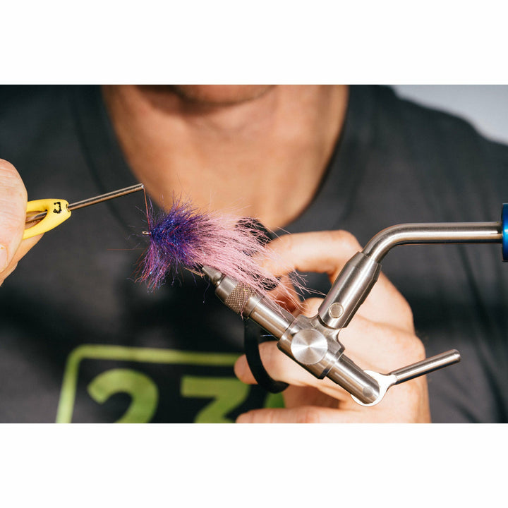 Adjusting fuzzy purple and pink fibers on fly tying vise