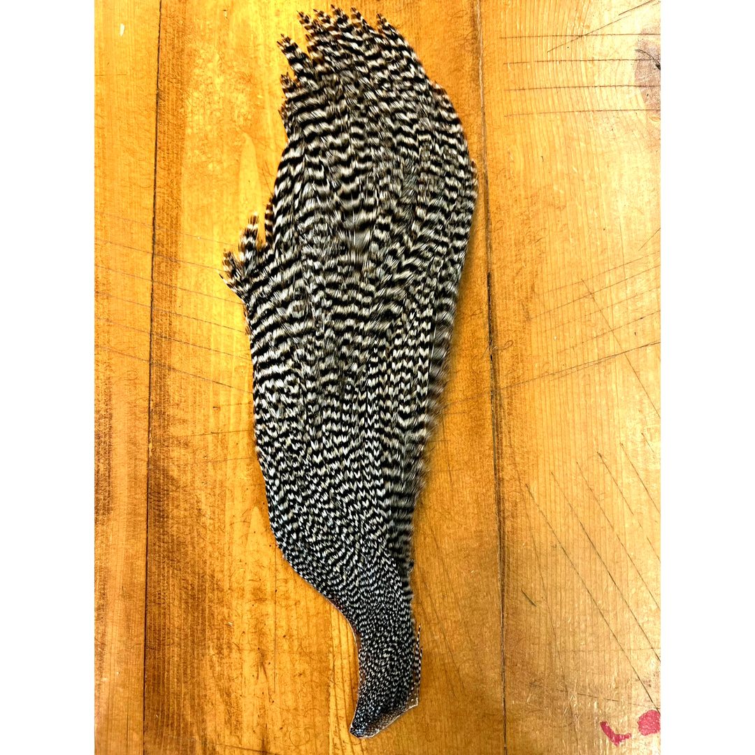 High-contrast black and white grizzly half cape fly tying feather on wood