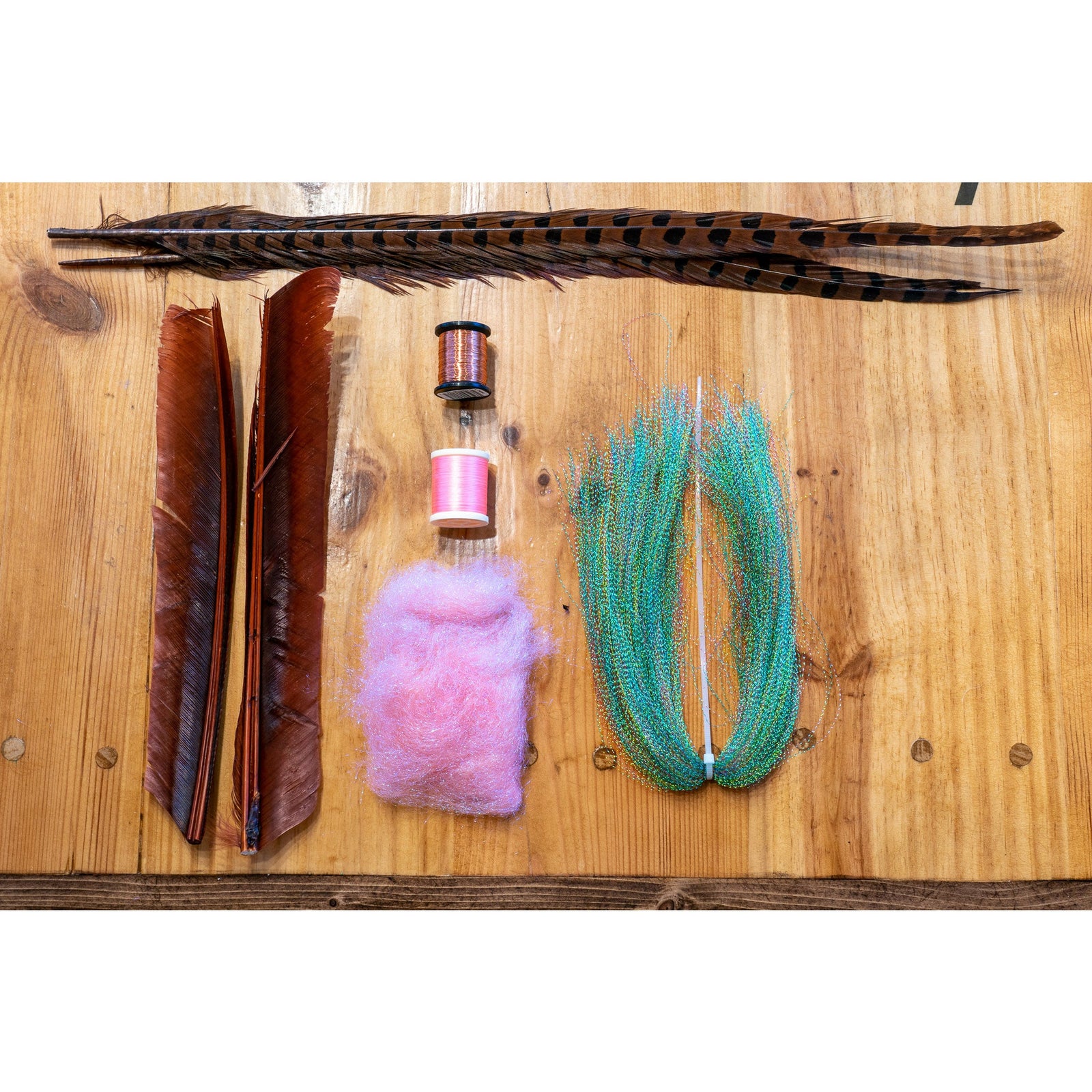Fly tying kit contents including pheasant feathers, copper wire, and pink dubbing