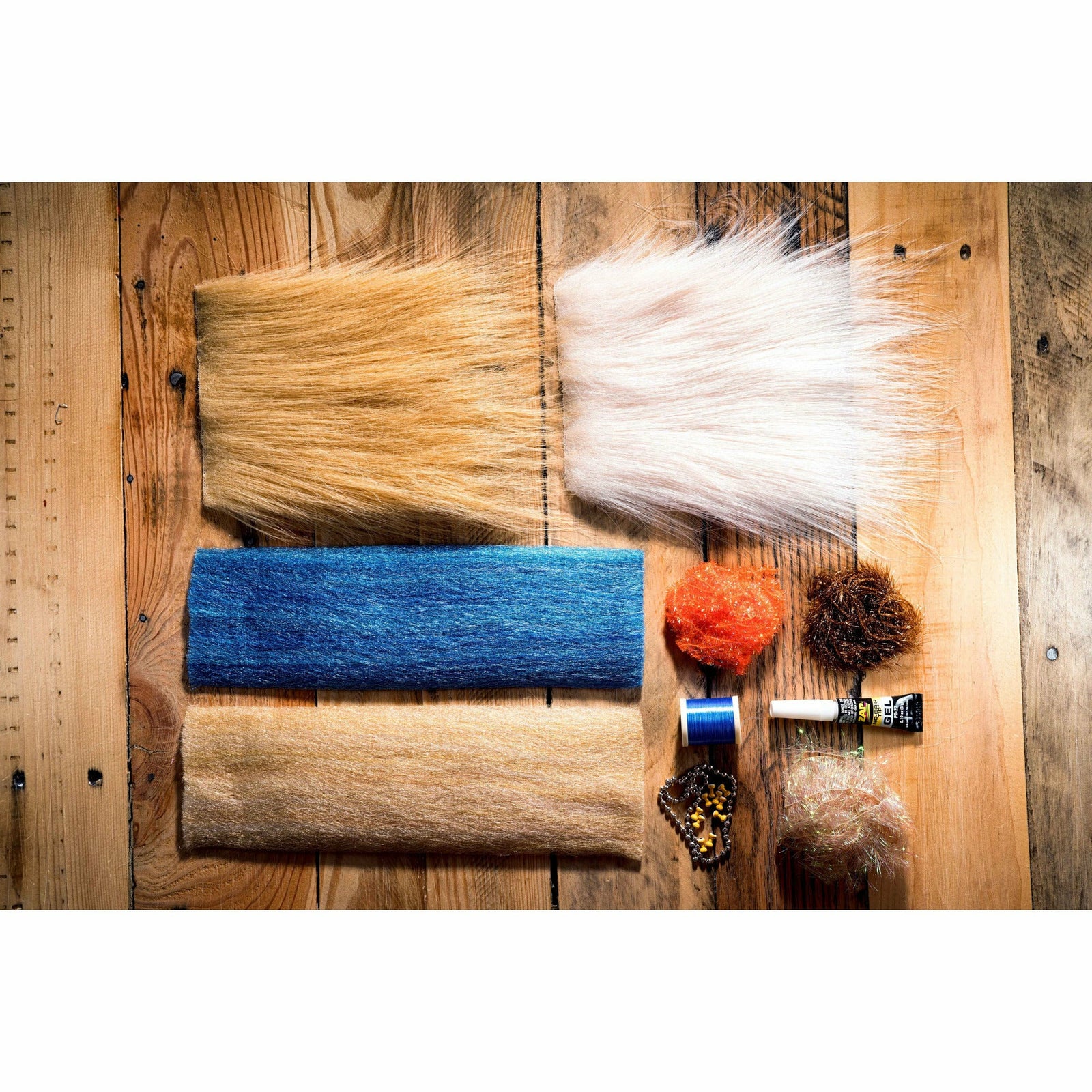 Gangster Crab DIY fly tying kit flat lay with blue thread, orange fur, and brown fibers