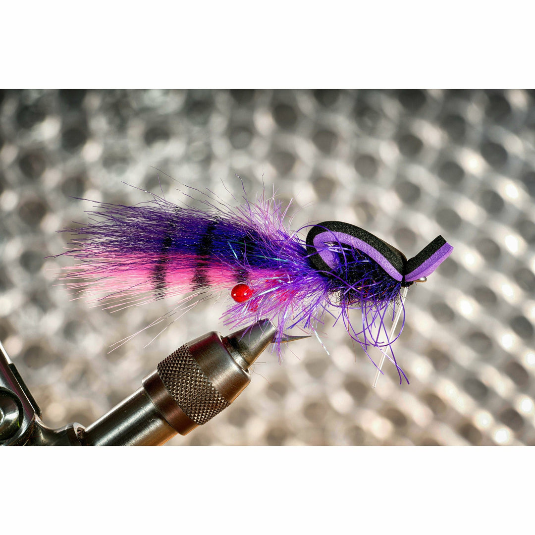 Close up of neon grape gangster gurgler fly on vise showing red bead eye and purple fibers