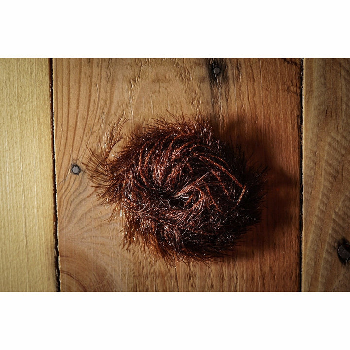 Brown Krystal Hackle fly tying material with metallic flash on wood