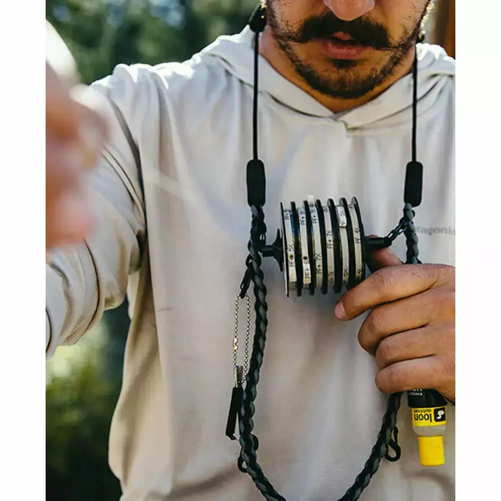 Angler wearing Loon Neckvest Lanyard holding fishing essentials