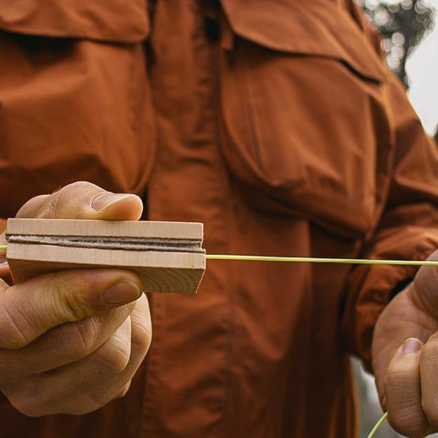 Using wooden block with sheepskin to clean yellow-green fly fishing line