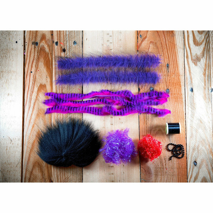 Megalolipop HD DIY Fly Tying Kit materials: neon purple marabou, black beads, and red thread on wood