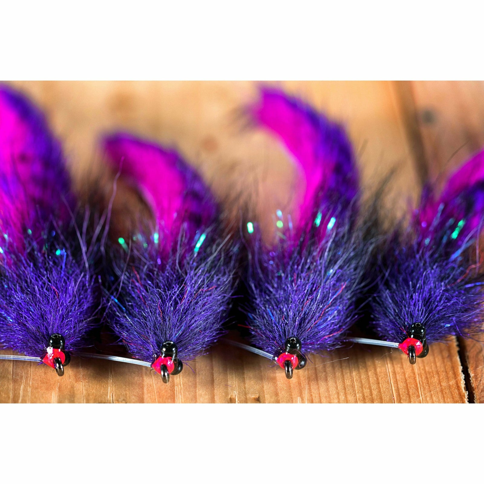 Completed Megalolipop fishing flies with black bead heads, purple chenille bodies, and barred purple tails