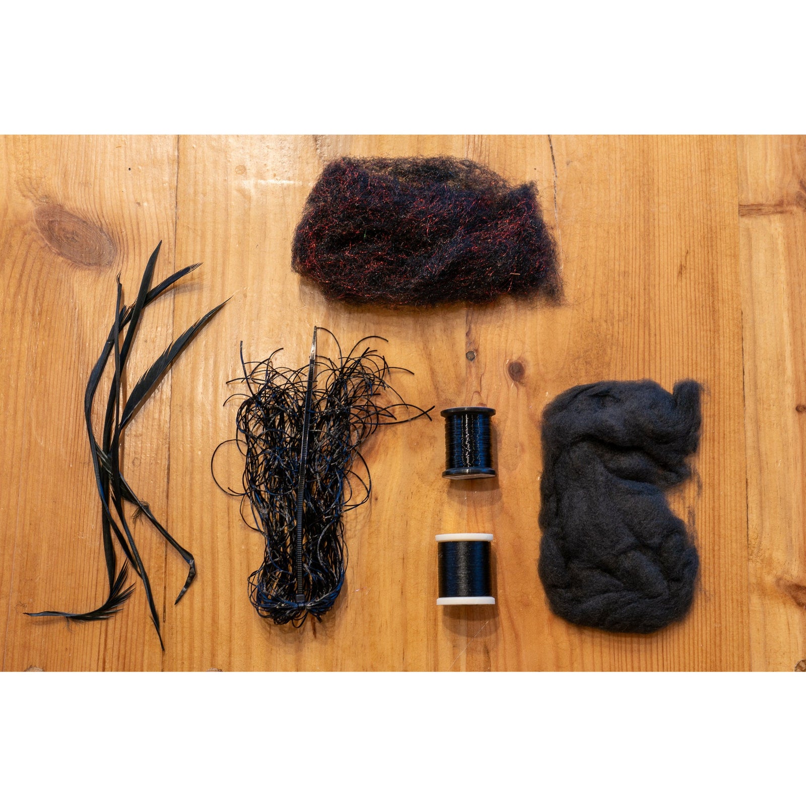 Fly tying kit materials including black goose biots, thread, and dubbing