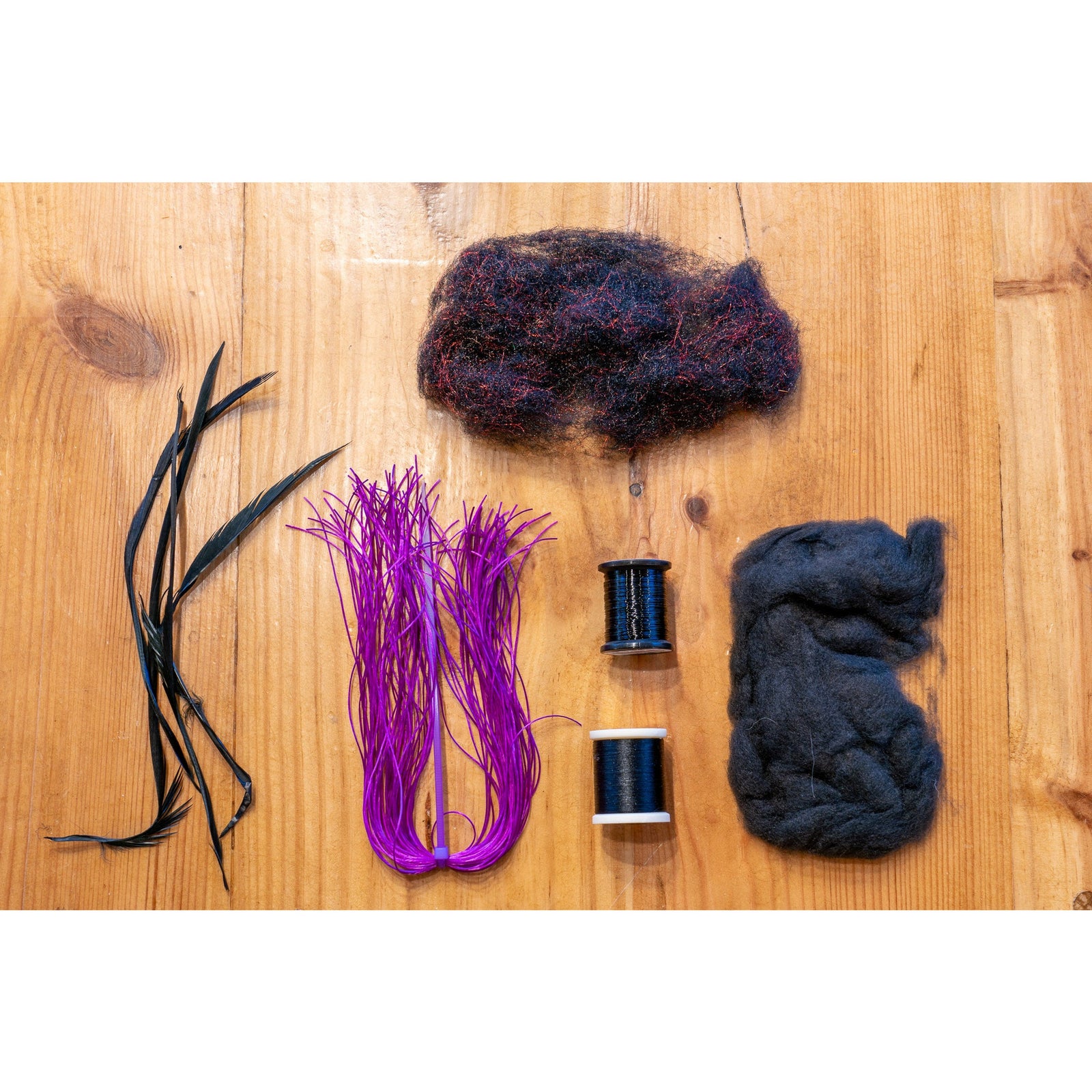 Fly tying kit materials including goose biots, purple flex floss, and dubbing